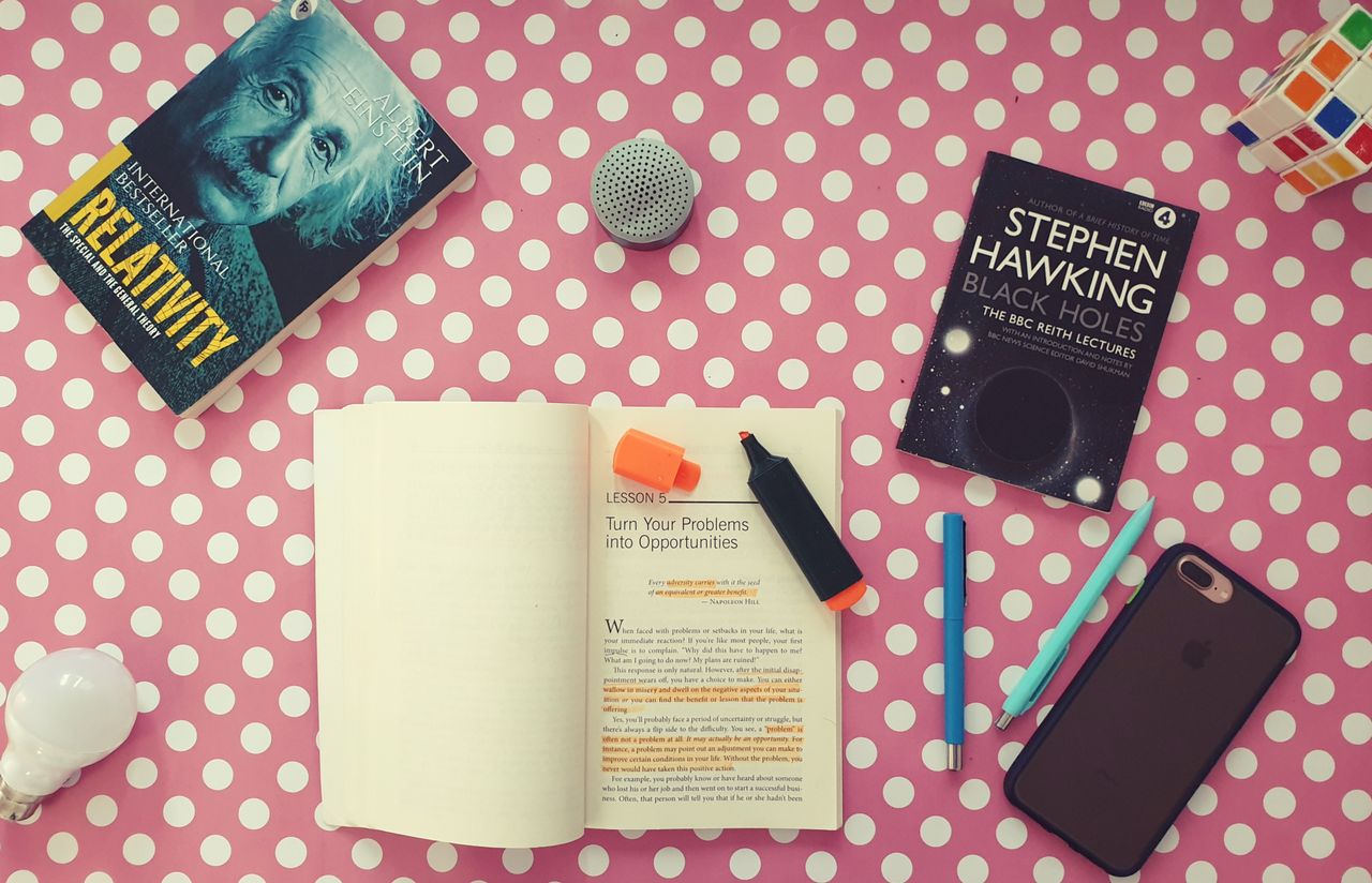 Offerings Flat lay of books, stationery, and gadgets on a polka dot desk for a vibrant study setup.